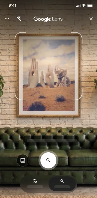 En un teléfono, se abre la app de Google Lens. Una notificación indica que la usuaria puede presionar el botón del obturador para buscar una imagen de esculturas de manos de piedra grandes en un desierto.